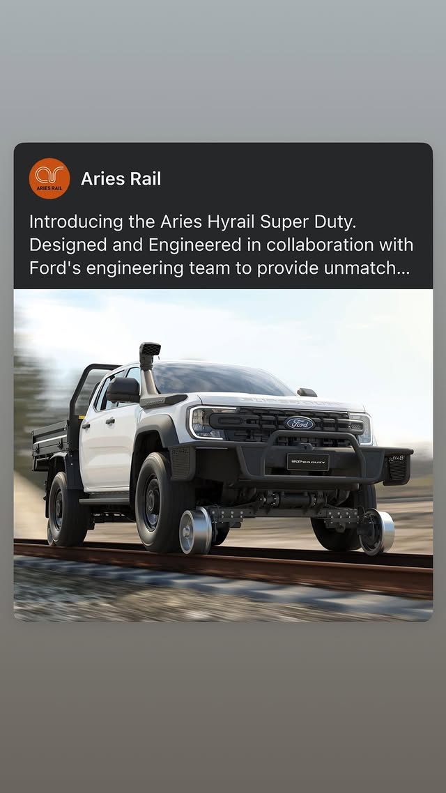 White Ford Super Duty pickup truck with black grille customizations and open driver door, mounted on railway tracks in motion