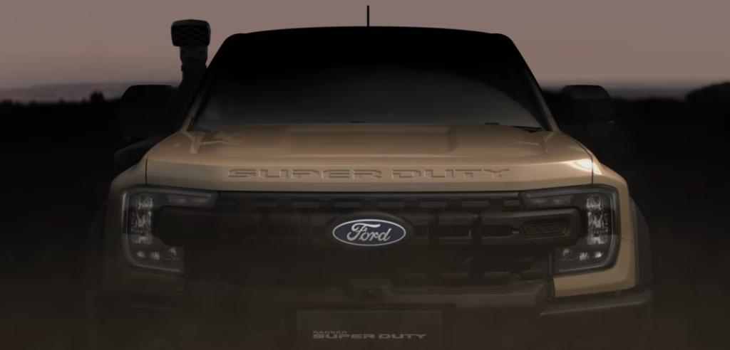 Front view of a Ford Super Duty truck photographed at dusk with warm golden lighting against a dark sky and blurred background