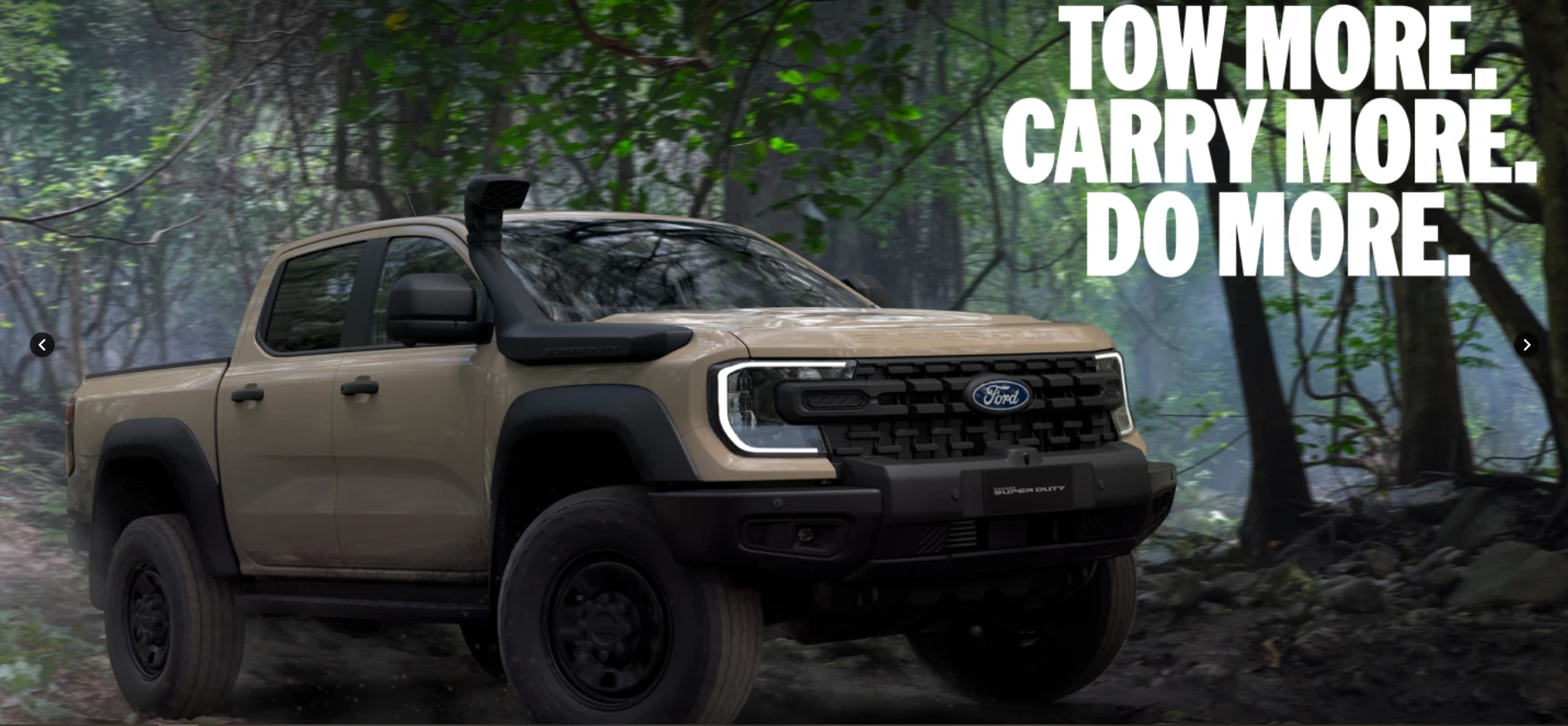 Tan and black Ford pickup truck parked on a forest road with dense green trees in the background